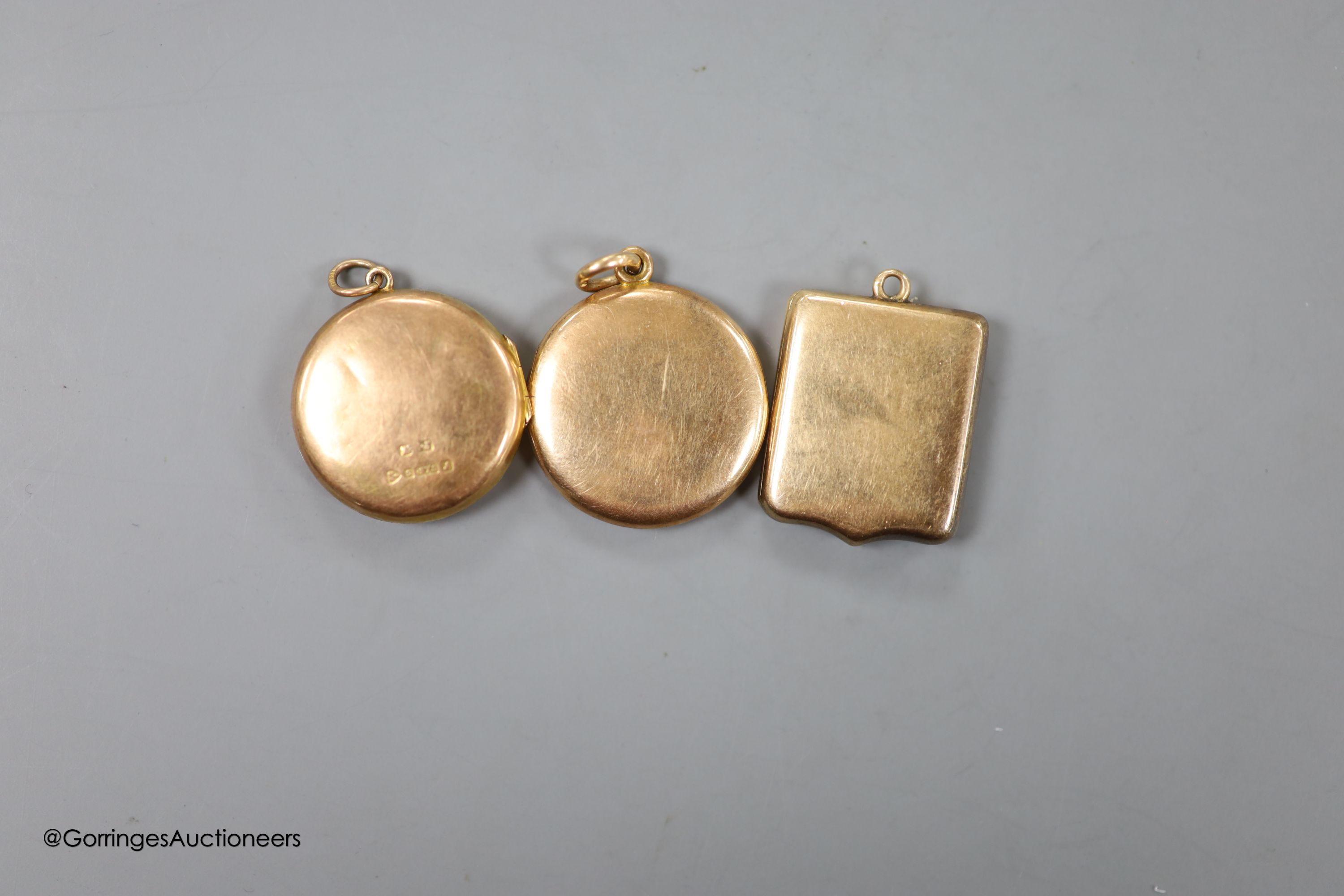 Three early 20th century yellow metal lockets, one stamped 9ct gold, all with engraved name or monogram, largest 24mm, gross weight 22.1 grams.